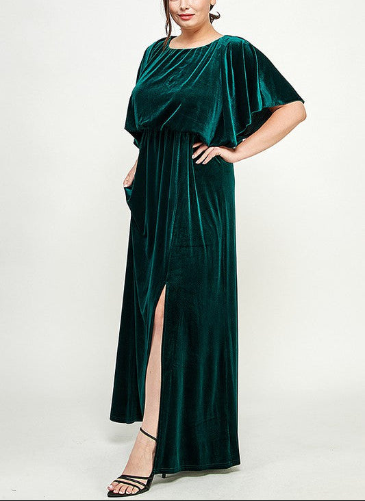 Woman wearing a green velvet dress with a slit on a white background