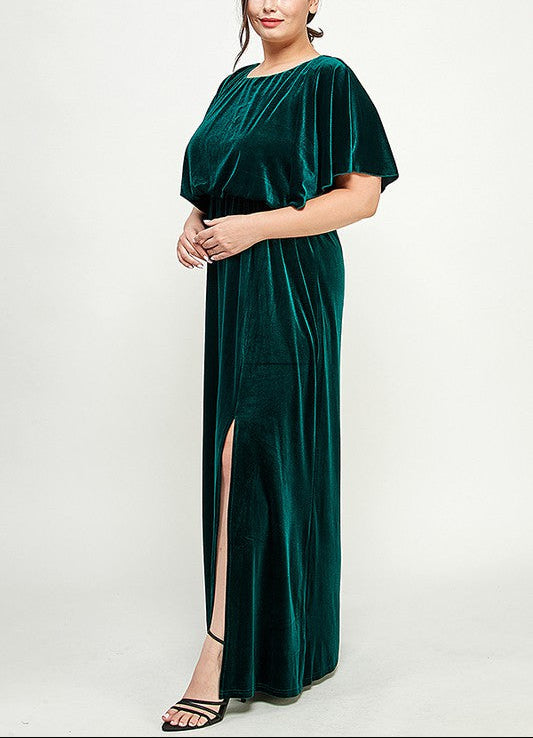 Woman wearing a green velvet dress with a slit on a white background