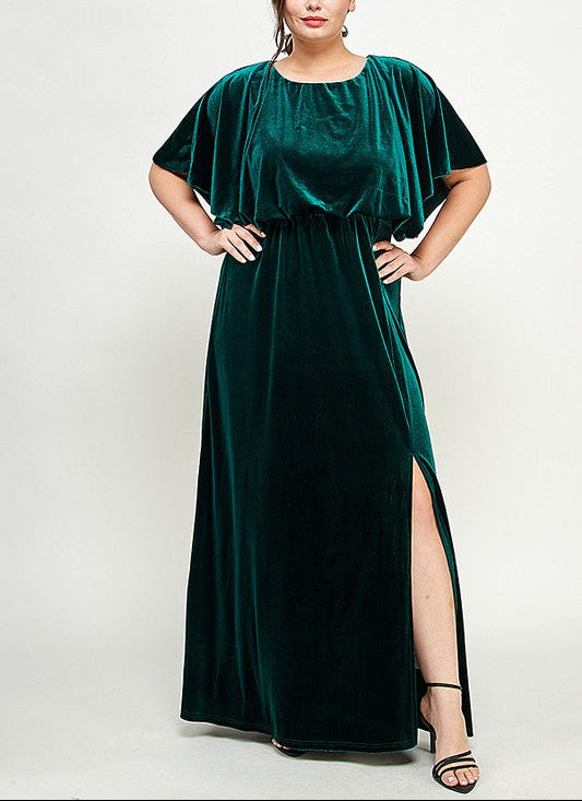 Woman wearing a green velvet dress with a slit on a white background